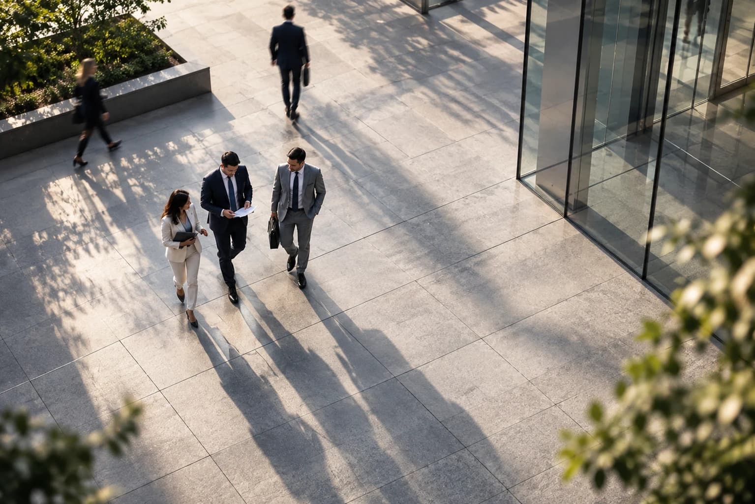Colleagues reading a document together as they cross a sunlit office plaza
